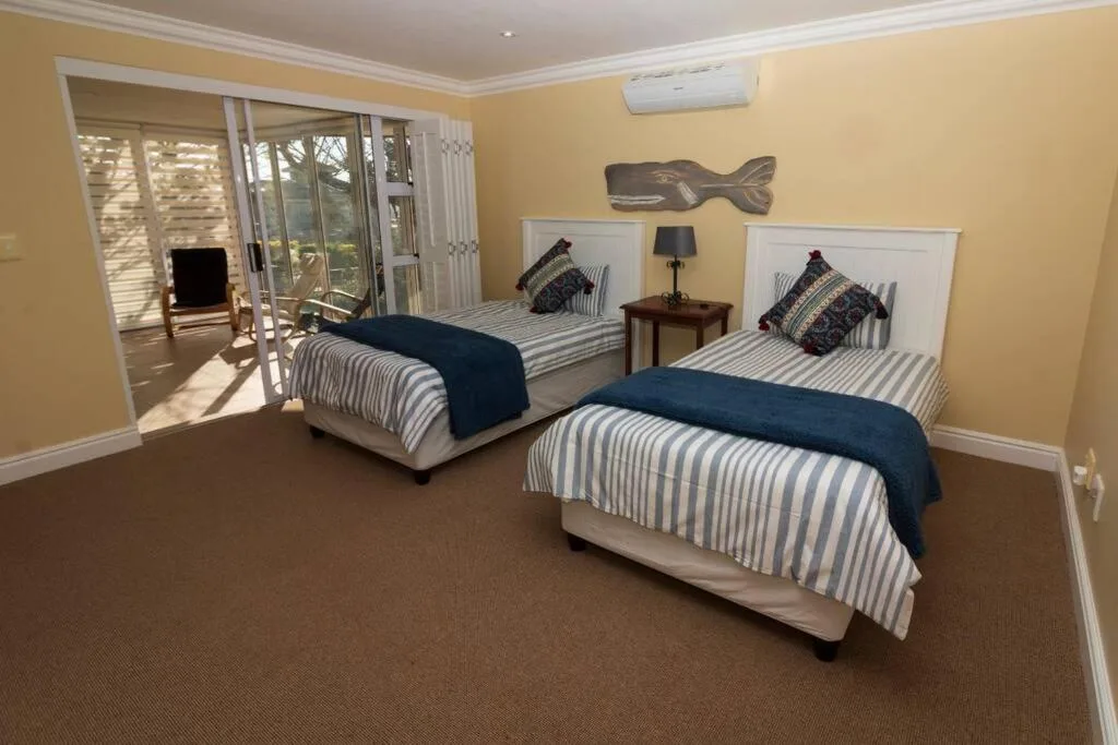 Spacious twin bedroom with striped bedding, sea-themed decor, and deck access