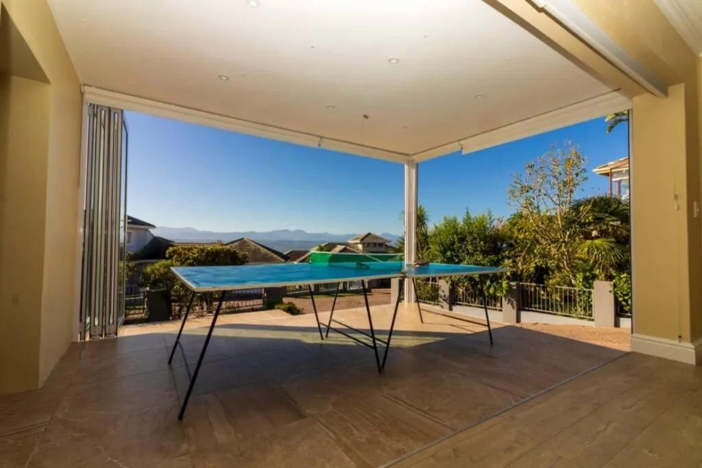 Covered deck with ping pong table overlooking swimming pool and mountain views