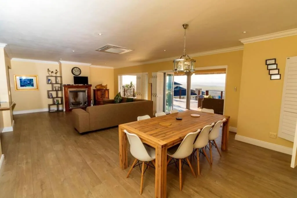 Bright yellow dining room with wooden table and cream chairs overlooking deck