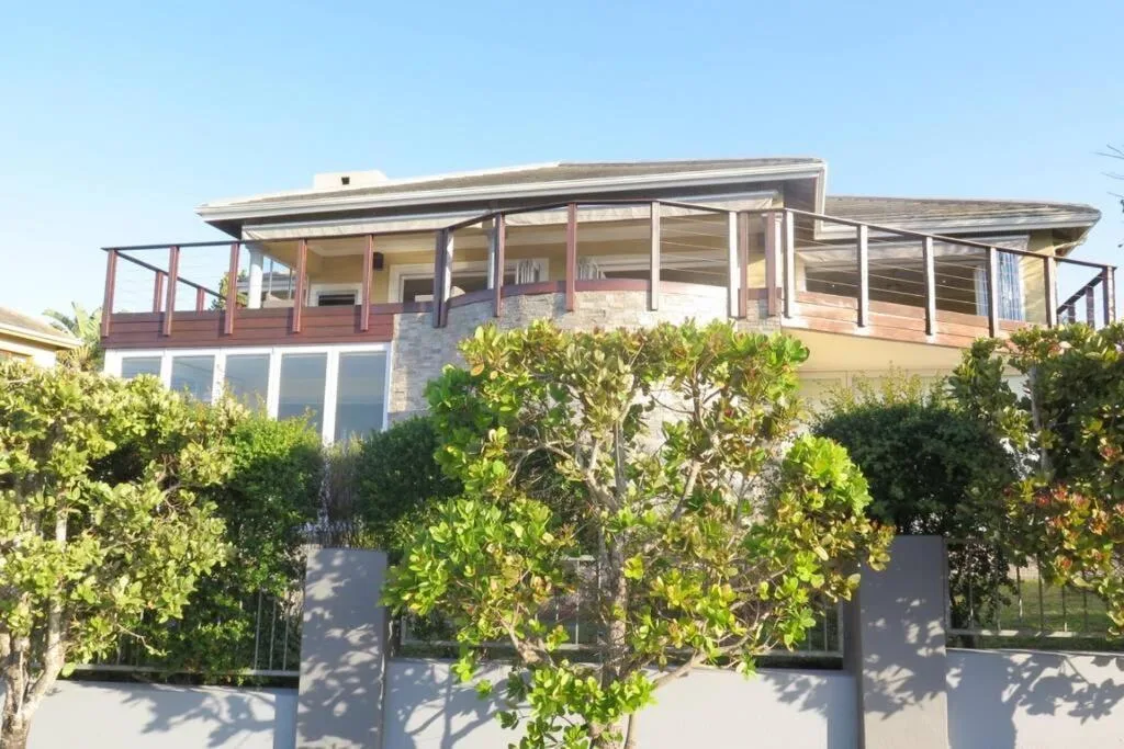 Modern two-story house with wraparound deck and lush green landscaping