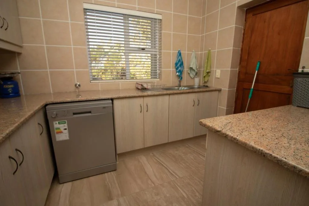 Modern kitchen with granite countertops, dishwasher, and window view