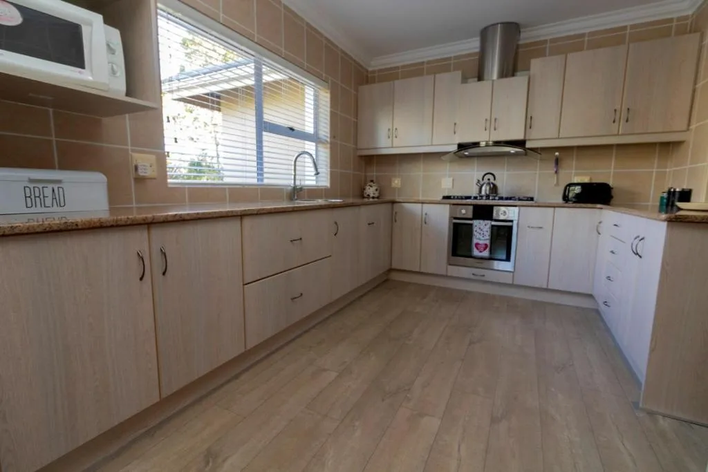 Spacious kitchen with white cabinetry, gas stove, and natural light from window