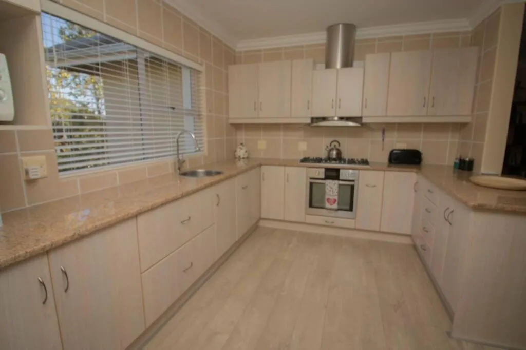 Modern white kitchen with gas stove, granite counters, and window view