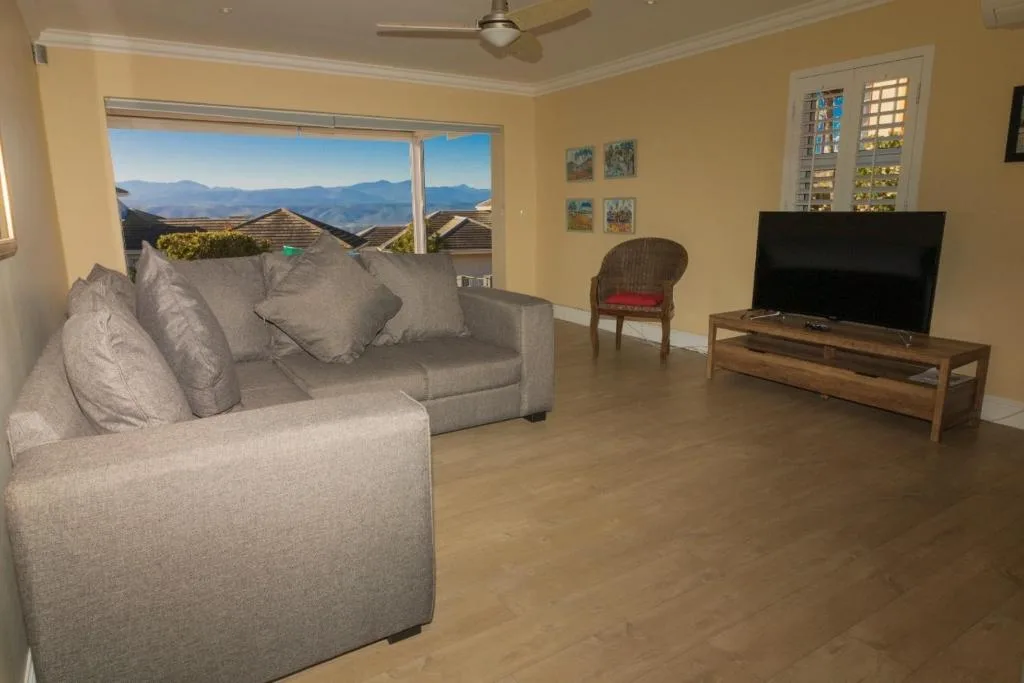 Spacious lounge with gray sofa, television, and mountain views through sliding doors