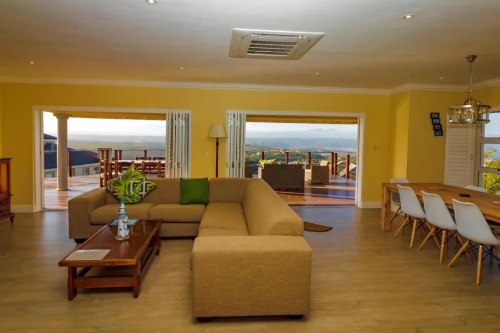 Bright yellow lounge with tan sectional sofa overlooking coastal views