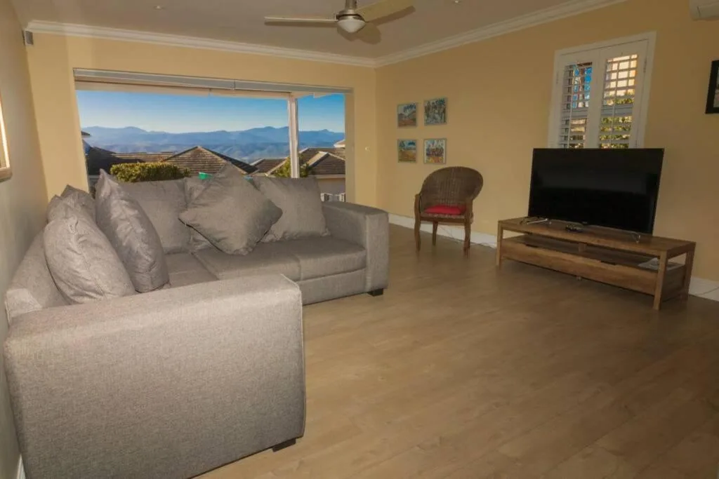 Spacious lounge with grey sofa, TV, mountain views through sliding glass doors