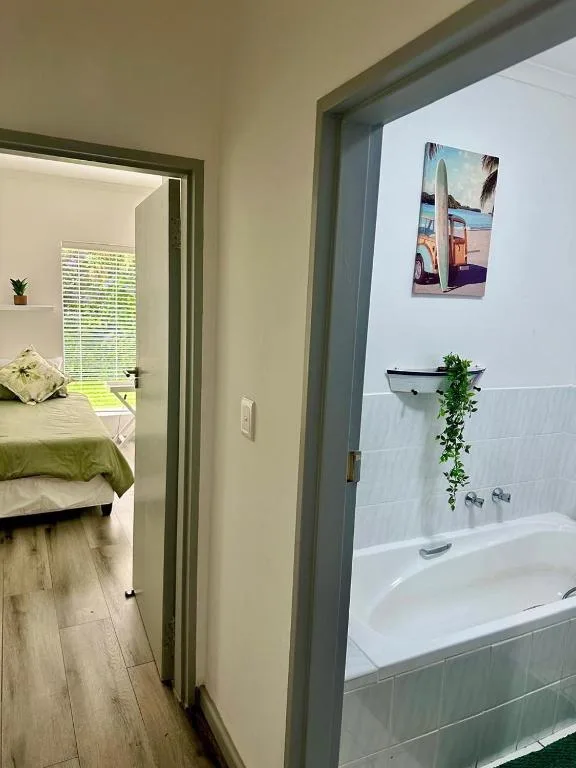 Modern bathroom with white bathtub, tiled walls, and green trailing plant decoration