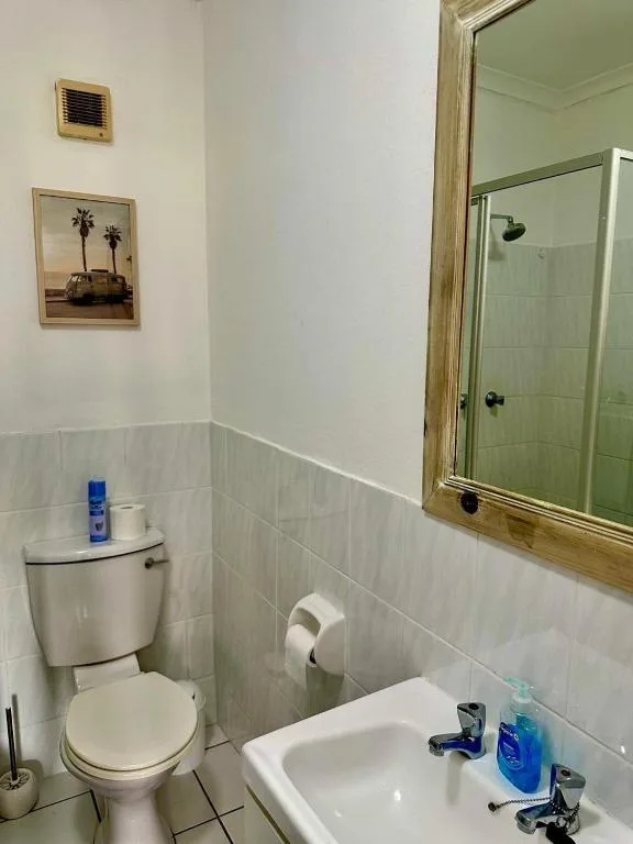 Clean bathroom with toilet, sink, mirror and white tile walls