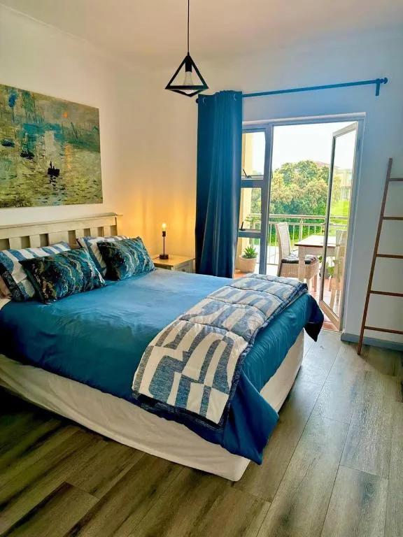 Bright bedroom with blue bedding, pendant light, and garden view doors