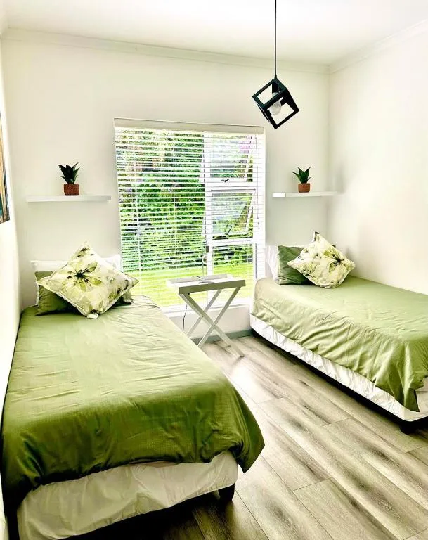 Bright bedroom with two twin beds and garden views through sliding doors