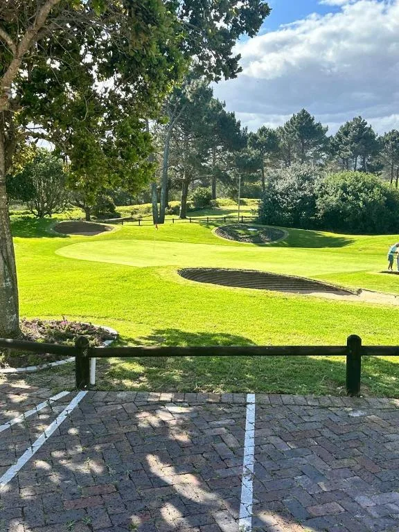 Paved patio overlooking lush green gardens and tree-lined grounds