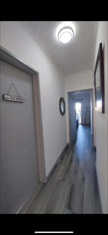Bright hallway with wooden flooring and bathroom door entrance
