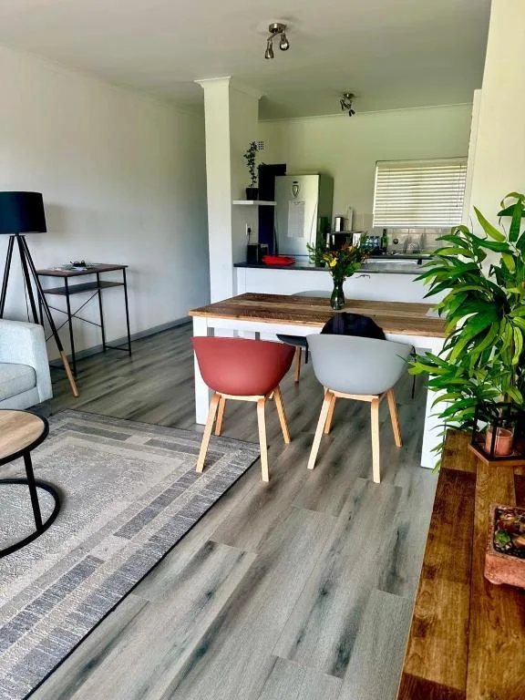 Open-plan dining area with wooden table and colorful modern chairs