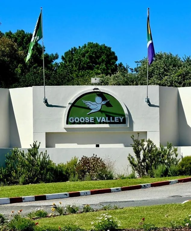 Goose Valley entrance sign with white facade and flags