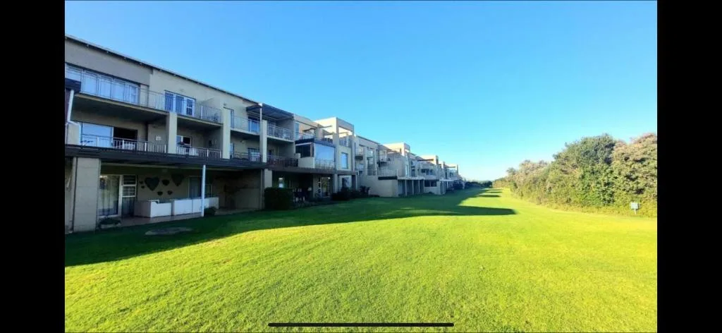 Modern apartment building with balconies overlooking manicured green lawn