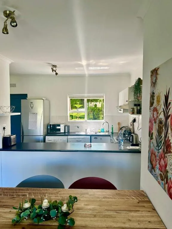 Modern kitchen with blue cabinetry, stainless appliances, and bright windows