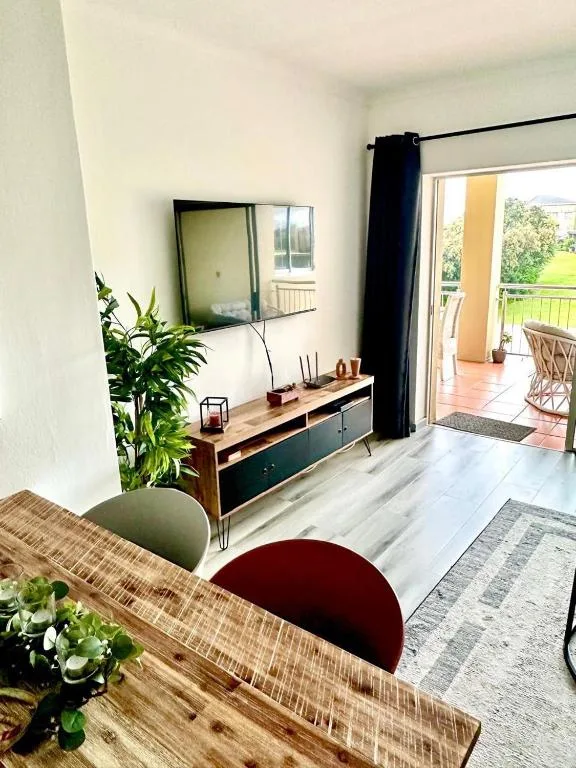 Bright lounge with TV, wooden desk, plants, and patio access