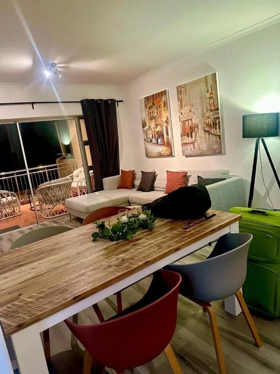 Modern lounge with sofa, dining table, and ocean view through glass doors