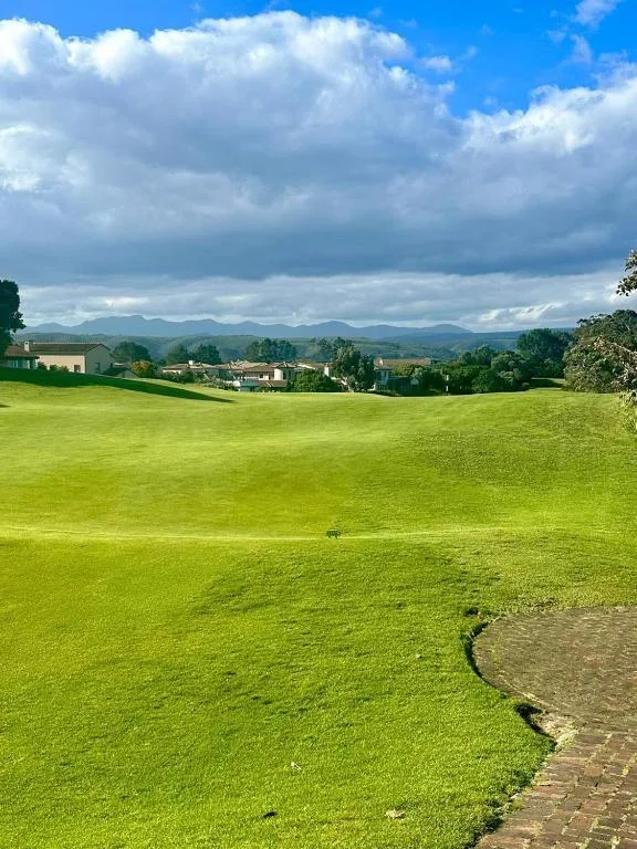 Sweeping mountain valley landscape with lush green lawns and distant peaks