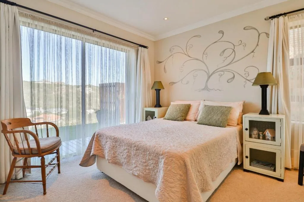 Spacious bedroom with queen bed, decorative wall art, and garden views through sliding doors