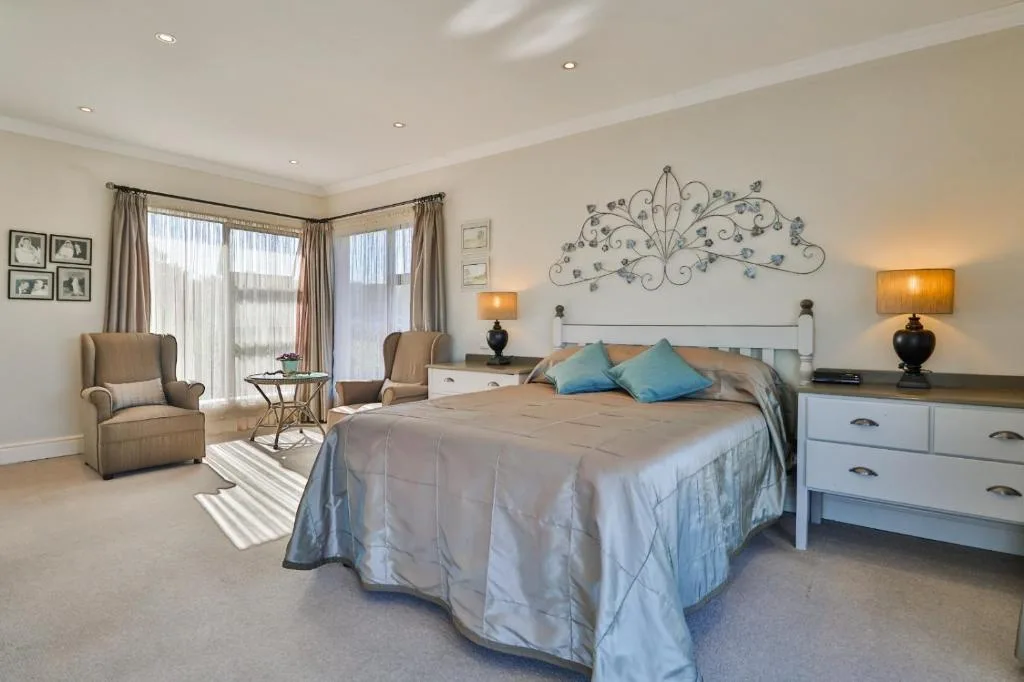 Spacious master bedroom with king bed, lounge seating, and ocean views