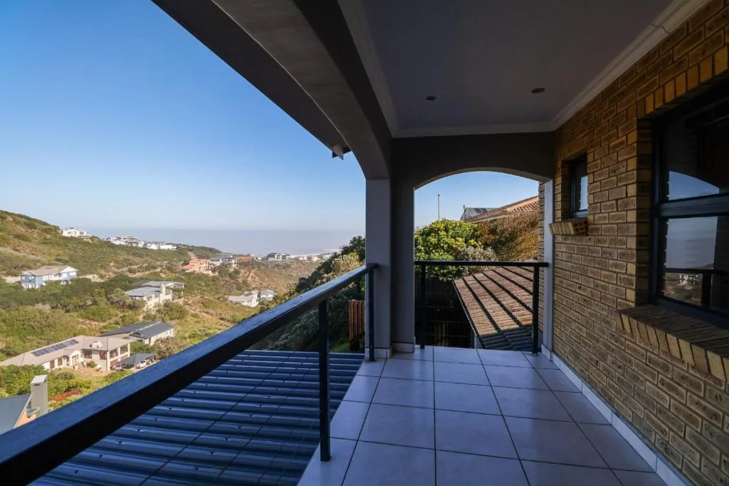 Spacious covered deck with valley and coastal views, blue railing, modern tiling