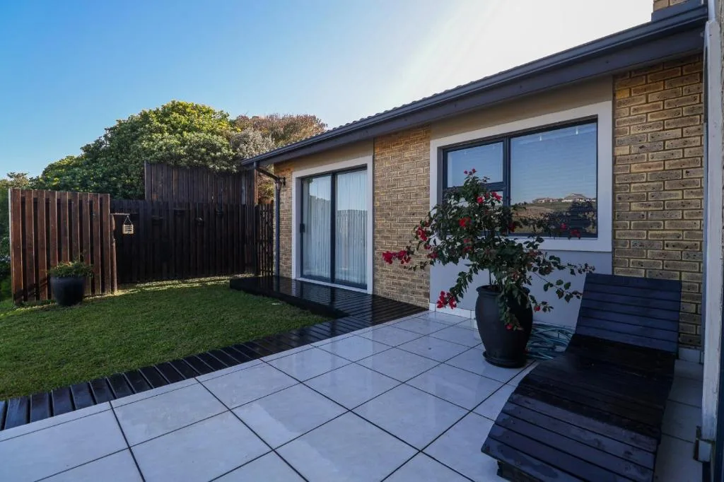 Modern patio with paving, potted flowers, and garden seating area