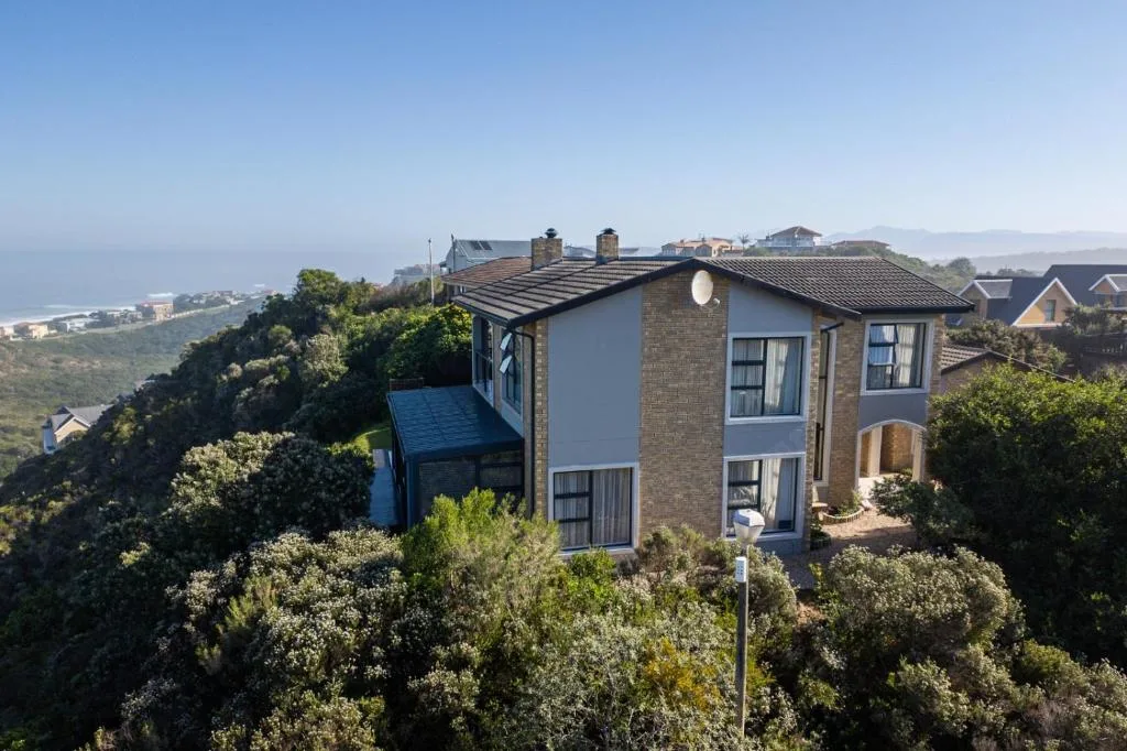 Modern two-story home with blue accents overlooking coastal landscape