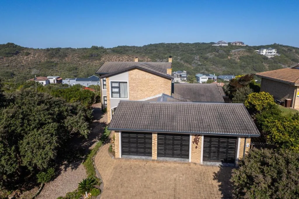 Modern brick home with dark roof and triple garage doors on Garden Route hillside