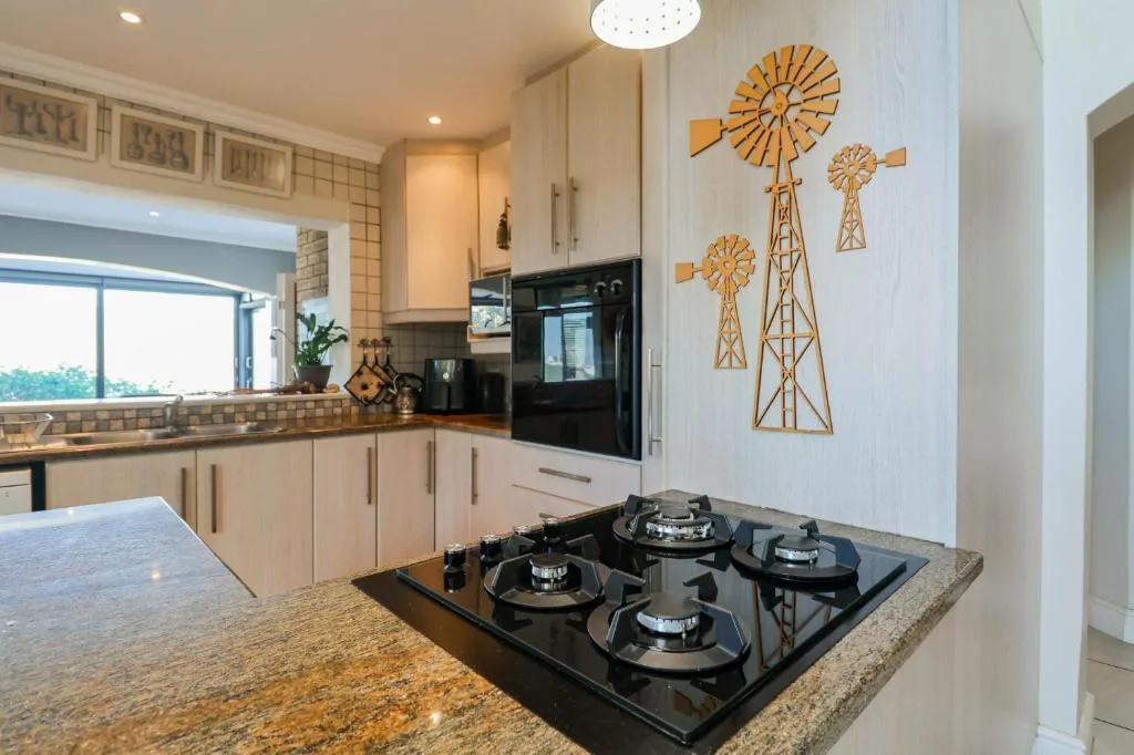 Modern kitchen with gas cooktop, cream cabinetry, and windmill wall art