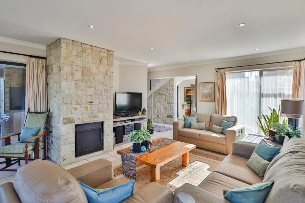 Spacious lounge with stone fireplace, comfortable seating, and garden views