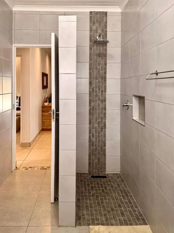 Modern bathroom with walk-in shower, grey and white tiles, frameless glass door