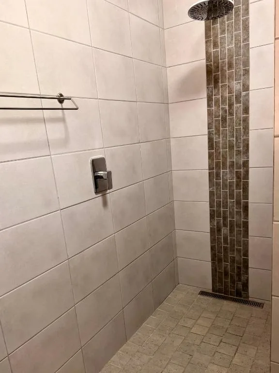 Modern walk-in shower with white tiles and rainfall showerhead