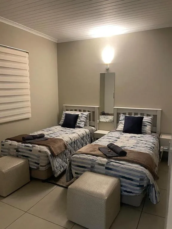 Twin beds with striped bedding and black accent pillows in bright bedroom