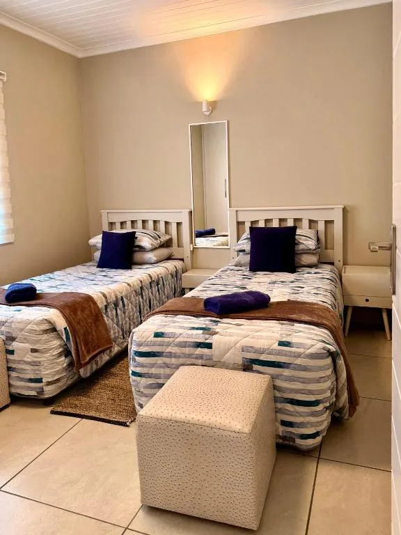 Twin bedroom with striped bedding, navy pillows, and wall mirror