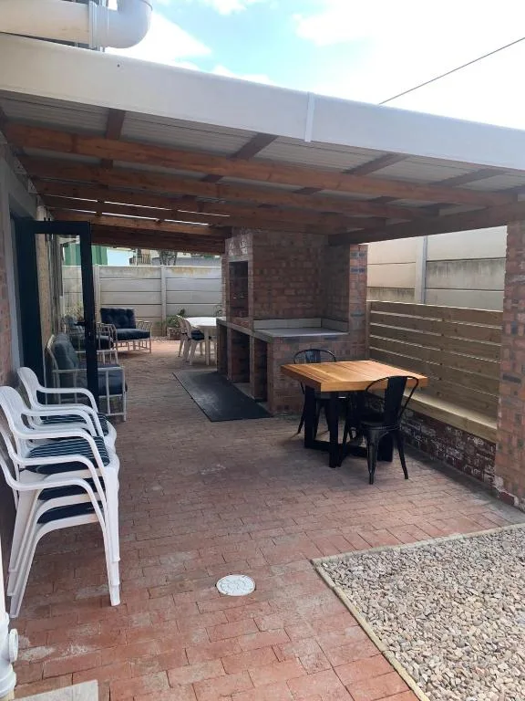 Covered patio with dining table, seating, and braai area