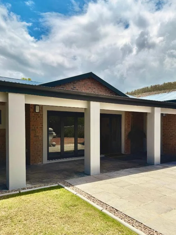 Modern house entrance with white columns and brick facade overlooking lawn