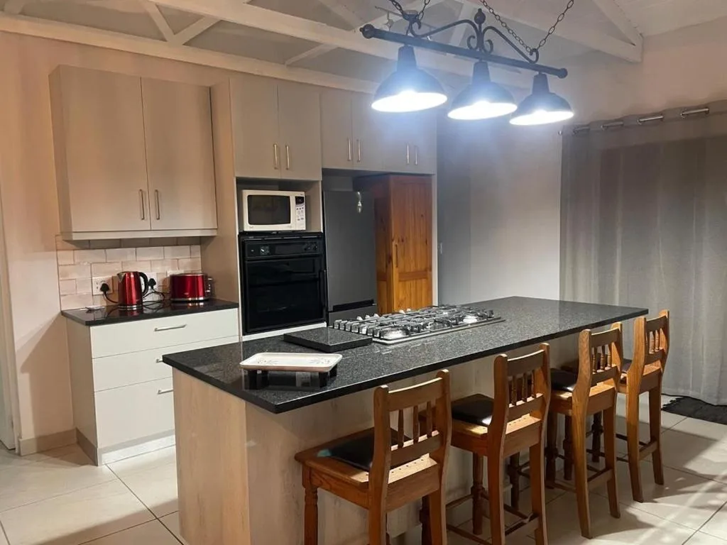 Modern kitchen with white cabinetry, black countertop, gas cooktop, and dining island