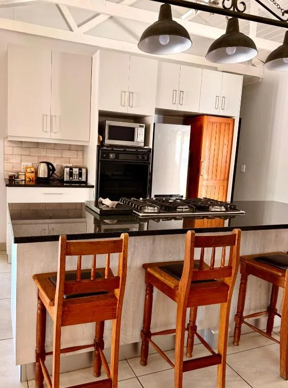Modern kitchen with white cabinetry, black countertops, and wooden bar seating