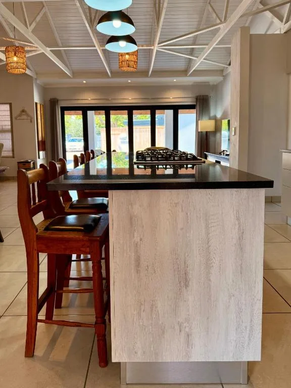 Modern kitchen with island counter, wooden bar stools, and view to lounge area