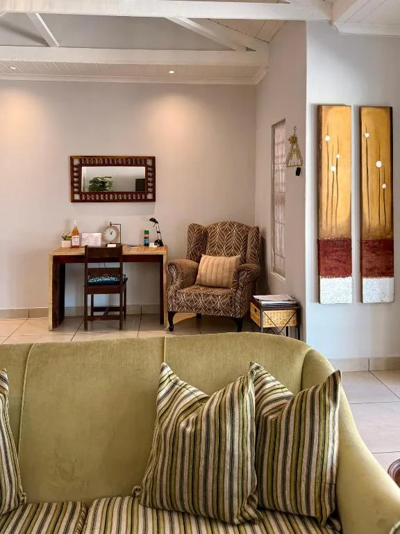 Bright lounge with green sofa, armchair, desk, and decorative mirror