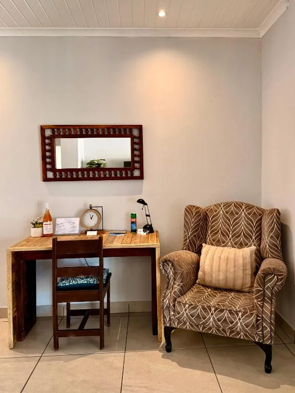 Cozy lounge corner with patterned armchair, wooden desk, and decorative mirror