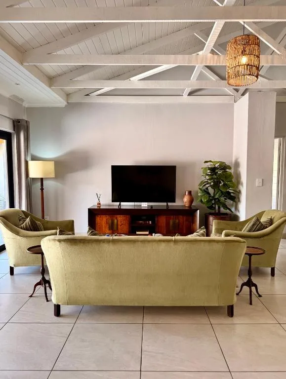 Modern living room with cream sofa, TV console, and exposed beam ceiling