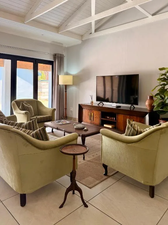Bright lounge with yellow armchairs, TV, wooden furniture, and large windows