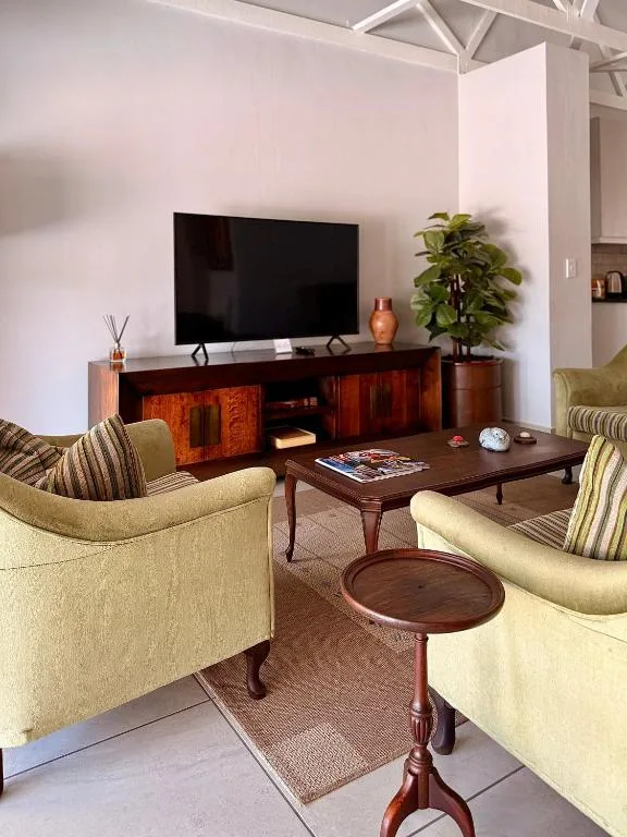 Elegant living room with cream armchairs, wooden TV stand, and coffee table