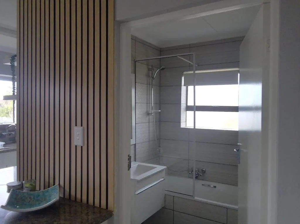 Modern bathroom with glass shower enclosure and grey tile walls