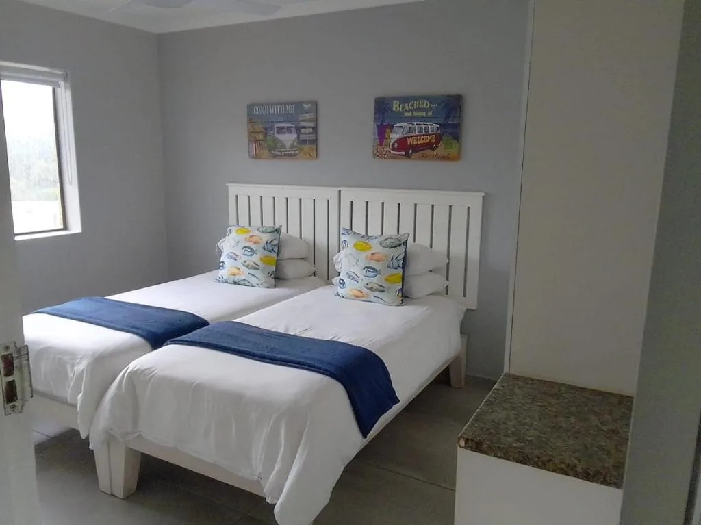 Twin beds with white headboard and colorful beach-themed cushions