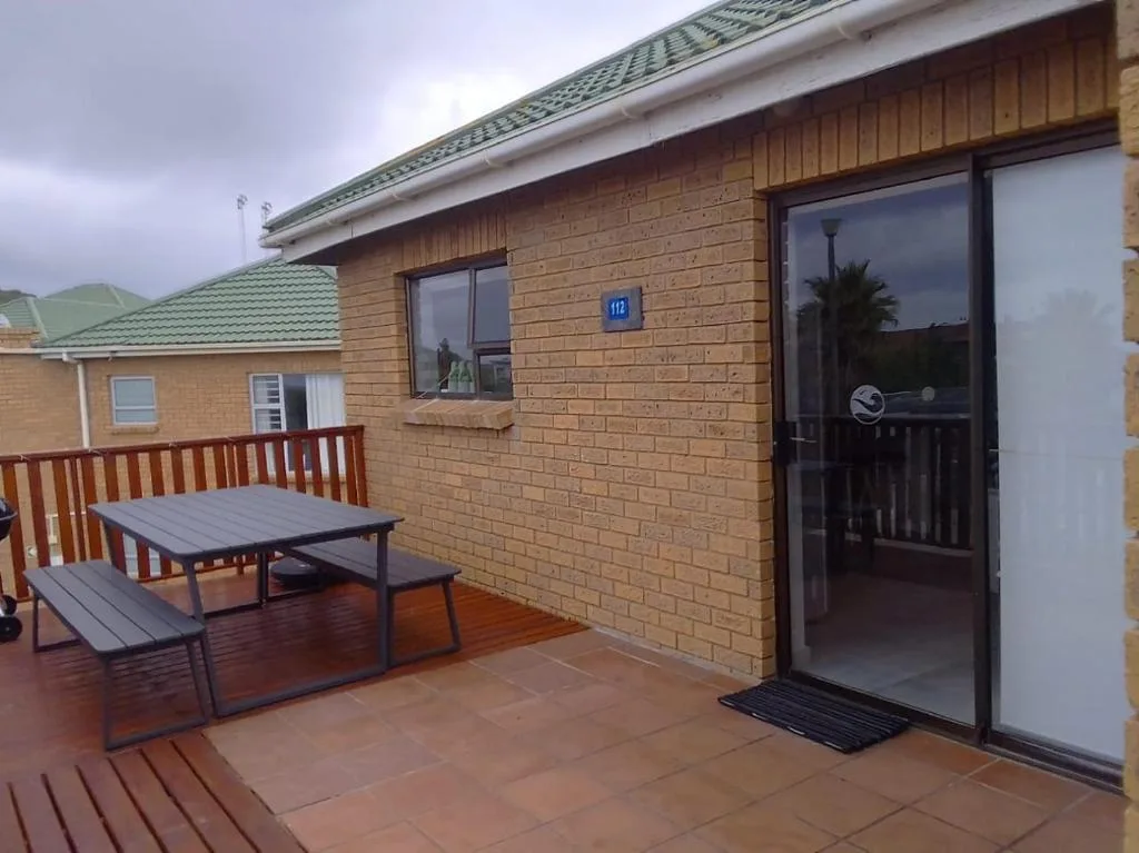 Spacious wooden deck with picnic table and brick building entrance