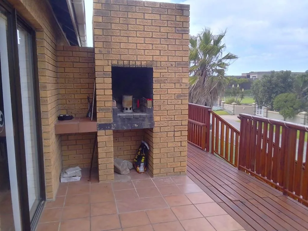Wooden deck with brick braai area and palm tree overlooking garden