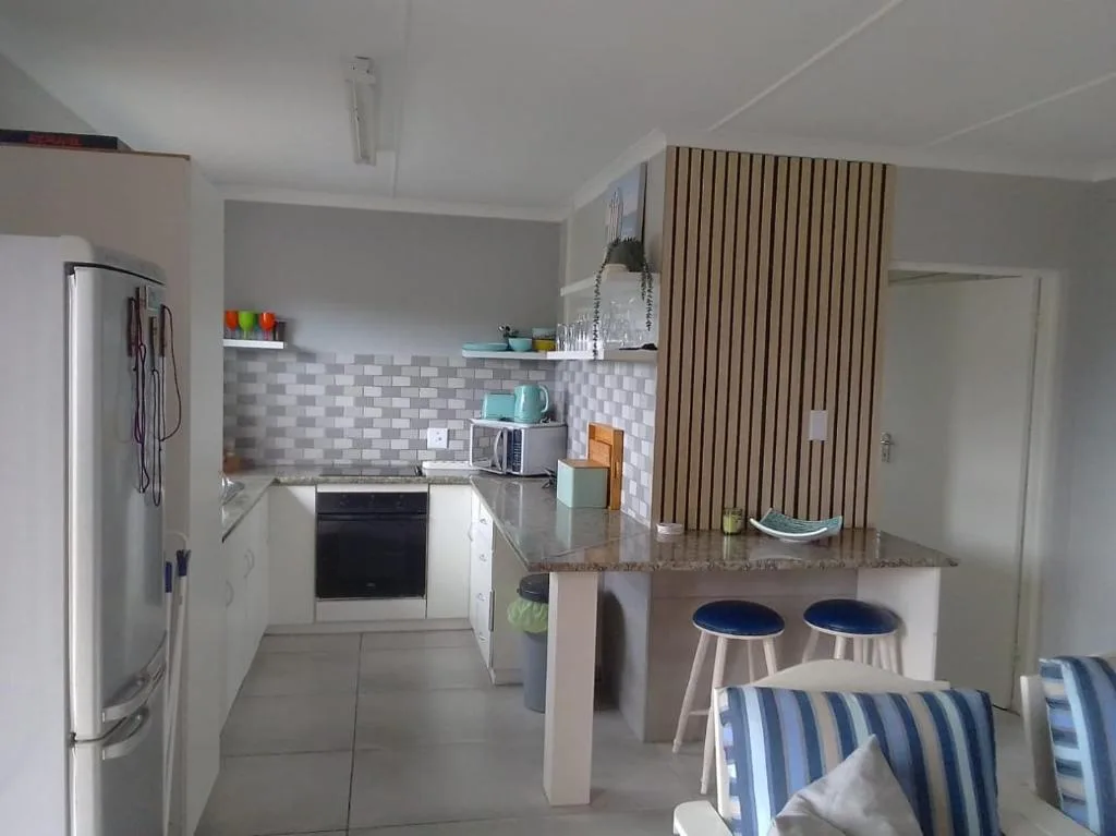Modern kitchen with white cabinetry, stainless steel fridge, and breakfast bar seating